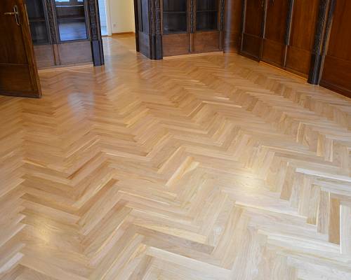 Fischgrätparkett in großzügigem Büro mit Durchgang und Einbauschränken.