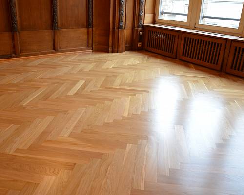 Fischgrätparkett im historischen Büro mit dunkler Holzvertäfelung und Fensterfront.