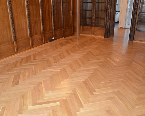 Altbauraum mit restauriertem Fischgrätparkett und historischer Wandverkleidung.