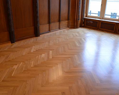 Hochwertiges Fischgrätparkett vor klassischer Holzvertäfelung im Altbau.