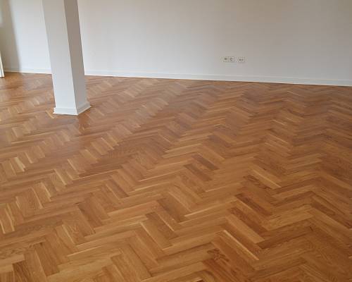 Detailansicht eines neu aufgearbeiteten Fischgrätparketts im Altbau.