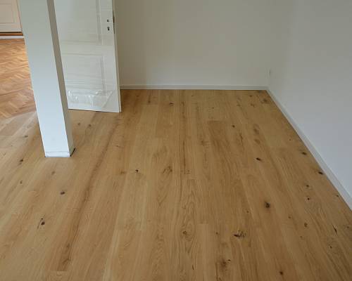 Schlafraum mit hellen Landhausdielen und sichtbaren Astanteilen.