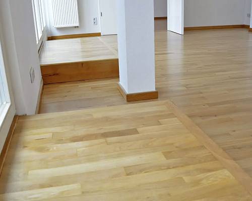 Wohnraum mit heller Stabparkettfläche und integrierter Podeststufe.