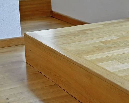 Podestkonstruktion mit passgenau verlegtem Parkett und Massivholzkante.