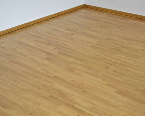 Heller Raum mit warmem Holzton und ruhiger Parkettoptik.