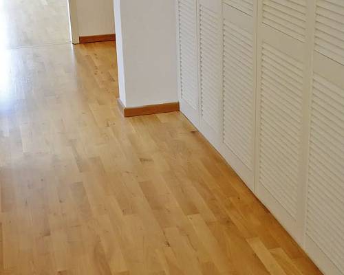 Flur mit durchgehendem Stabparkett und weißen Lamellentüren.