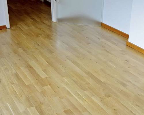 Wohnbereich mit sauber verlegtem Parkett und umlaufender Sockelleiste.