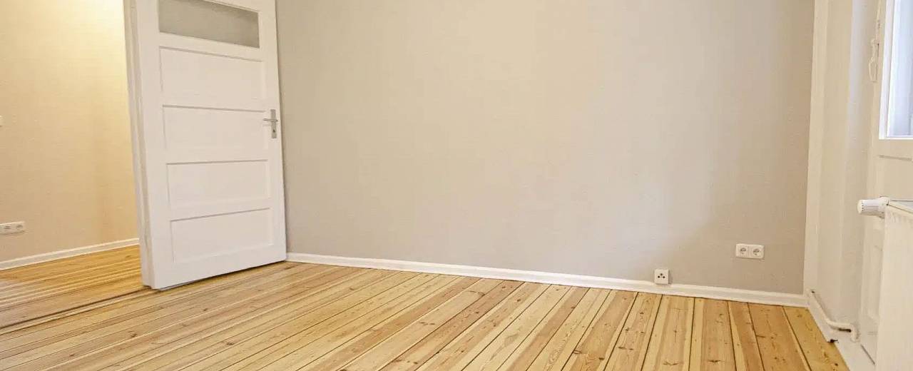 Heller, frisch geschliffener und aufgearbeiteter Holzdielenboden im selben Raum nach der Renovierung.