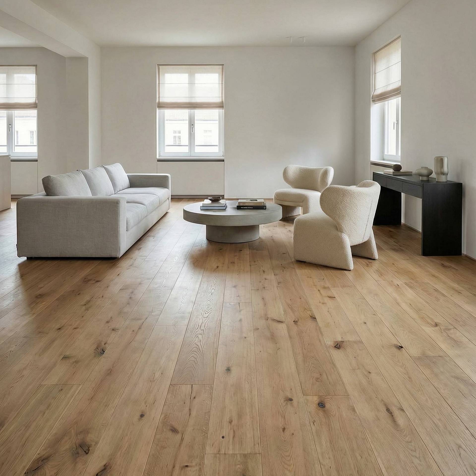 Wohnzimmer mit hellem Holzdielenboden, Sofa und Sesseln.