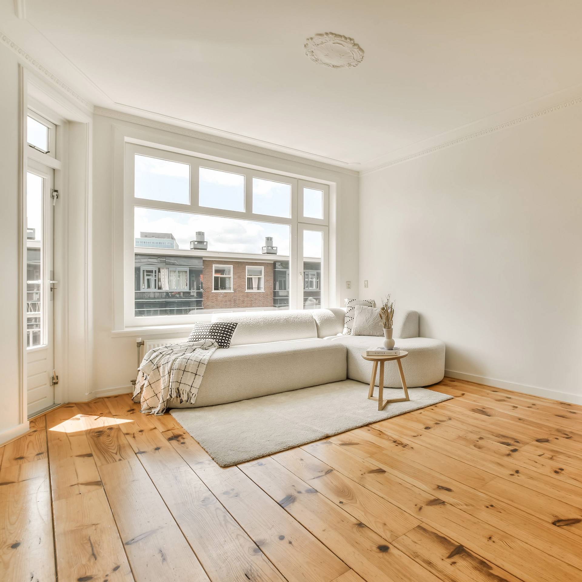 Heller Wohnraum mit großem Fenster und geöltem Holzdielenboden.