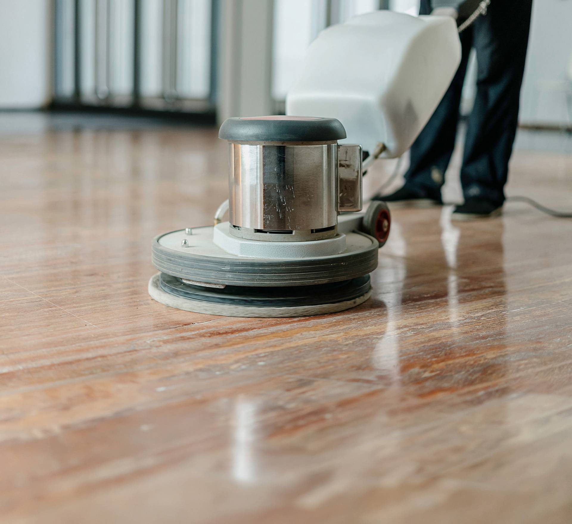 Professionelle Bodenmaschine reinigt und poliert einen Holzboden, die Oberfläche wirkt sauber und gleichmäßig glänzend.